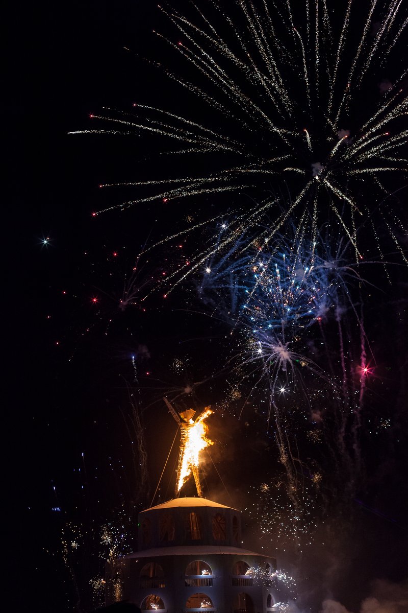 The man starts burning as fireworks light up the sky.