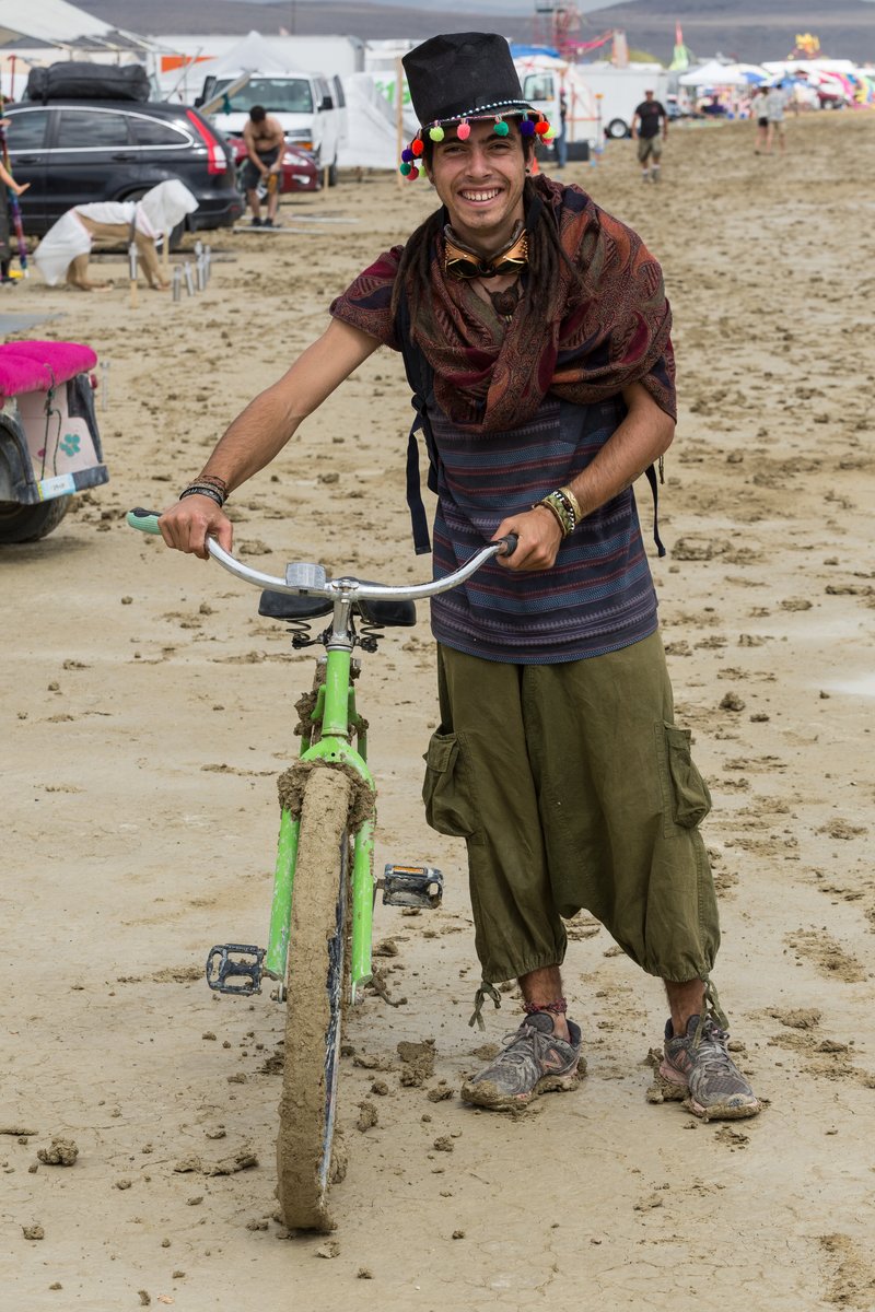 Man Happily Struggles With His Bike On The Wet Playa