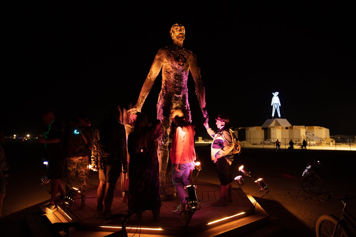 Passage by: Dana Albany from: San Francisco, CA year: 2018 Passage is an installation of a man, in a captive gesture, leisurely walking while its hand sweeps through stalks of wheat. The sculpture clearly highlights characteristics of a human form; muscle, sinuous tendon, sculpted hands, feet. Yet, it's a composite of mechanical debris and steel. Viewers may hypothesize, is this a man? is it part robot? and what is the blurry fine-line between each? The other huge component is the presence of the wheat. It symbolizes abundance, life, fertility. It is food, subsistence, of which without, the human race would be extinct. Viewers can look closer at the inherent beauty of the human form, contemplate mechanics/technology or most importantly, be reminded of our absolute reliance on nature in the end.