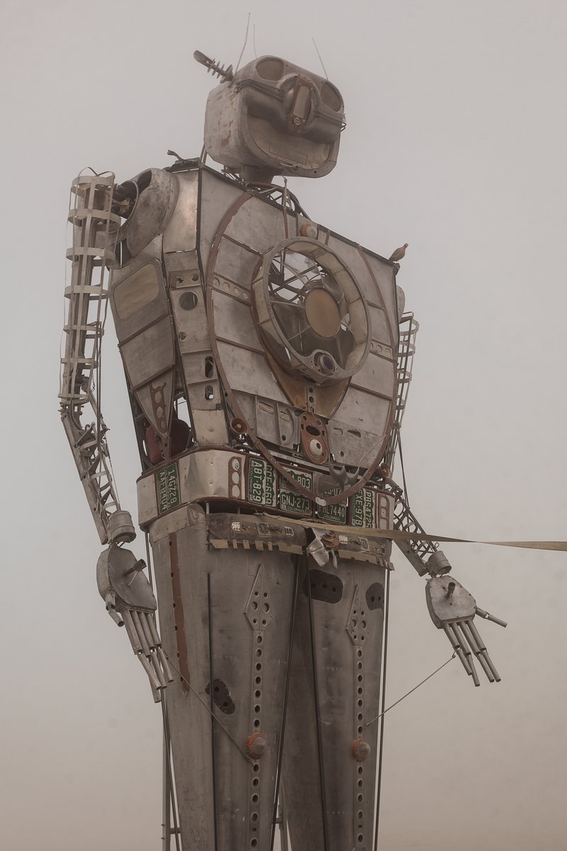 Robot Resurrection by: Shane Evans from: Denver, CO year: 2018 Robot Resurrection is towering 30 foot tall, human piloted, articulating sculpture made from reclaimed airplane parts and found objects. From the torso cockpit, the operator(s) manipulate the Robot's motions and fire effects. This piece is a representation of we all have become... Robots. It is a wake-up call of how large these problems are. We have been controlled for too long. Robot Resurrection was born from what we as a society have discarded. Our hope is that this 28′ Robot will inspire reflection upon one's self and be a reminder of the power we all hold. We hope it awakens some awareness of our situation and encourages some small change on a small scale that leads to big change in the massive system.