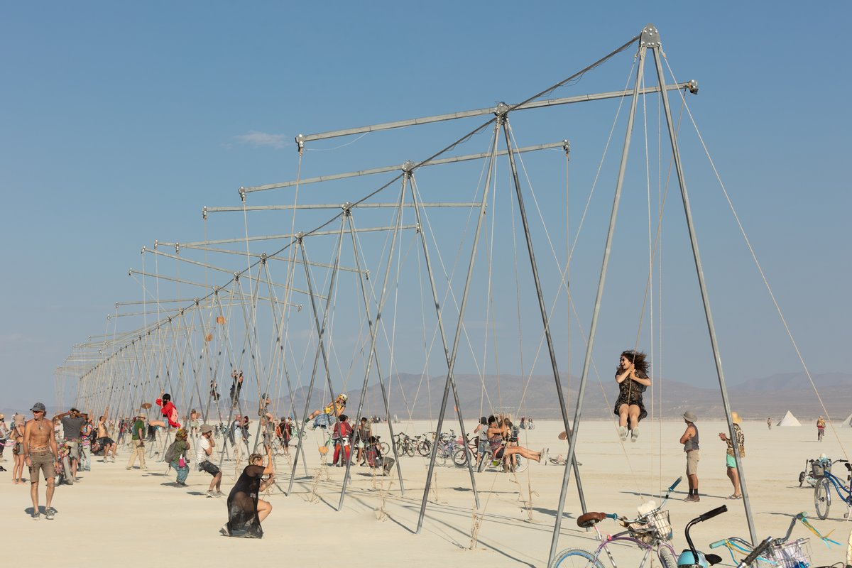 Burners playing on swings that are also seesaws.