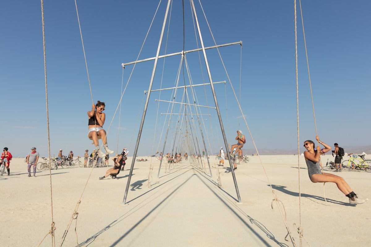 Burners playing on swings that are also seesaws.