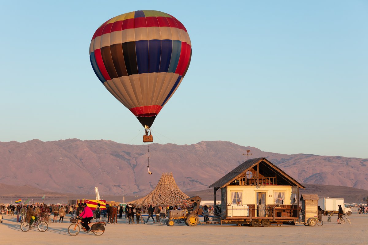 Strait No Chaser : The Great Strait Escape by: LadyBEAST and GatorDox from: Oakland, CA year: 2018 Strait No Chaser : The Great Strait Escape is a performance art installation in which Arianna (LadyBEAST) will be secured in a strait jacket and suspended by her feet from the basket of a hot air balloon. The piece is supported by a team from GatorDox camp. It is a radical expression of internal and external struggles gracefully suspended in a chaotic world.