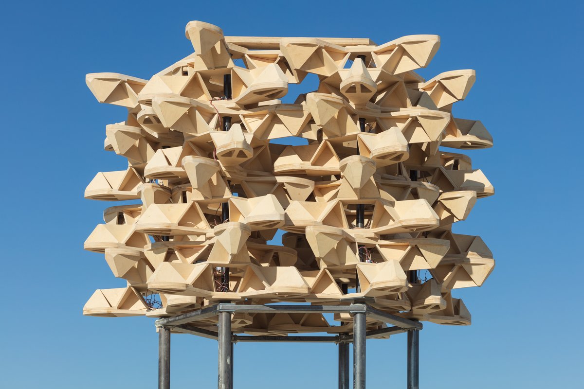 Big Pollinator by: Jakob Bokulich from: New York, NY year: 2018 At approximately 23 feet high, Big Pollinator seems to hover in the air, a machine of flower-like modules spinning in synchronicity. The shape of the modules creates an interplay of lights and shadows between the "flowers," making hexagons appear and disappear, ephemeral patterns suggestive of a beehive. Big Pollinator is about interconnectedness. People, weather patterns, animals, plants, the planet... We are all connected, like gears in a machine, or bees in a colony. We are part of the same organism. URL: http://bigpollinator.com
