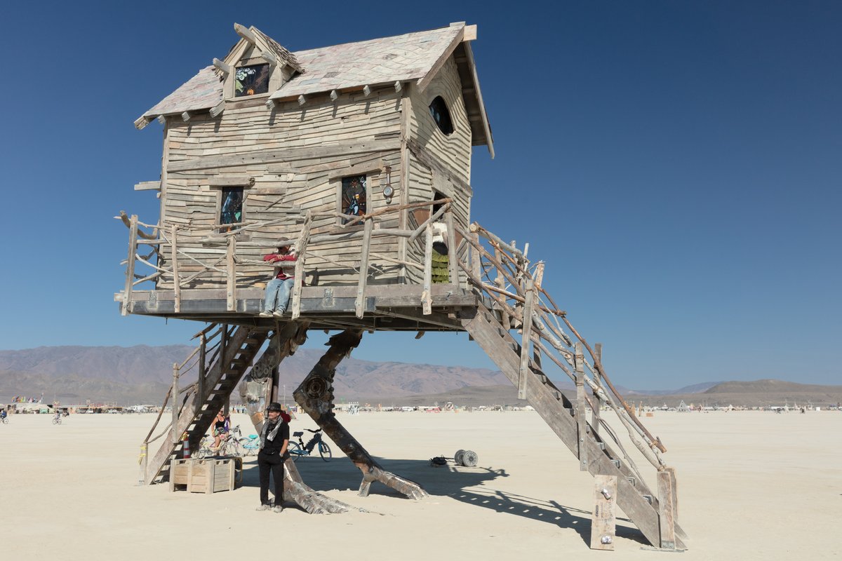 Baba Yaga's House by: Jessi Sprocket Janusee and Baba Yaga's Book Club from: Reno, NV year: 2018 The house of Baba Yaga will rise from the playa straddling it's mechanical chicken legs. The crone's house will be poised to run at the slightest provocation. Ascend her staircases to test the old witch if you dare. Are you able to walk through the veil of mortality into the space where the seer dwells? If you are strong of will, feeling bold and willing to show vulnerability she may allow you to venture within her sanctum. URL: http://jessisprocket.com/baba-yaga/