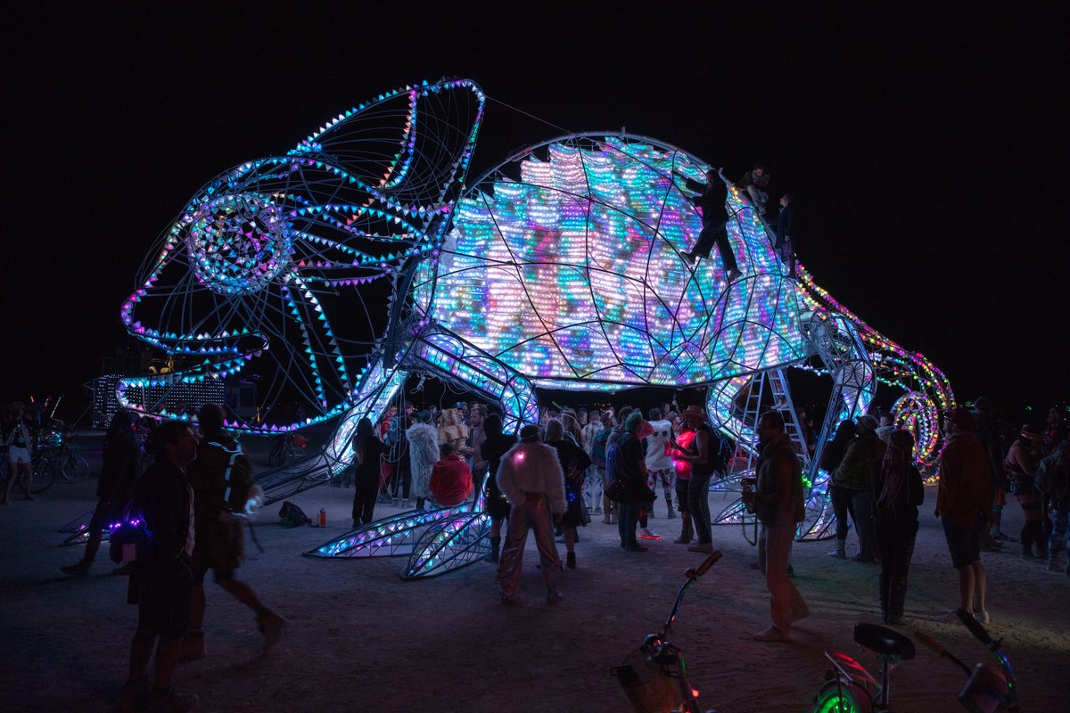 Come-Million! by: Amit Weissenstern from: Tel-Aviv, IS year: 2018 Come-Million is a giant colorful chameleon that shines up beautifully when playing interactively with her friends! Come-Million's skin is made of hundreds of tiles carrying thousands little lights. Their colors change in reaction to the participants' behavior inside, sensed through its pumping heart. A playful collaboration is demonstrated through the interaction between the people inside the chameleon, and passerby. Inside the chameleon there will be an interactive game that the visitors and the chameleon will participate in using a set of handles of different colors. Citizens of Black Rock City will sense and understand Come-Million's through its signals and listen to her heart - to help her shine with millions of colors.