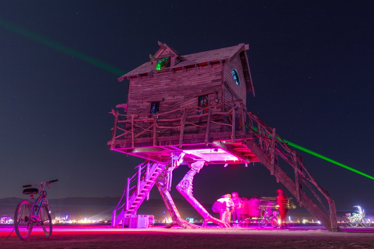 Baba Yaga's House by: Jessi Sprocket Janusee and Baba Yaga's Book Club from: Reno, NV year: 2018 The house of Baba Yaga will rise from the playa straddling it's mechanical chicken legs. The crone's house will be poised to run at the slightest provocation. Ascend her staircases to test the old witch if you dare. Are you able to walk through the veil of mortality into the space where the seer dwells? If you are strong of will, feeling bold and willing to show vulnerability she may allow you to venture within her sanctum. URL: http://jessisprocket.com/baba-yaga/