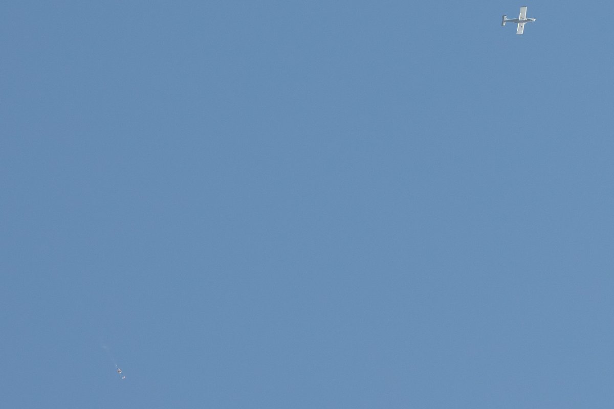 The skydiver's parachute opens and a little puff of playa comes out.