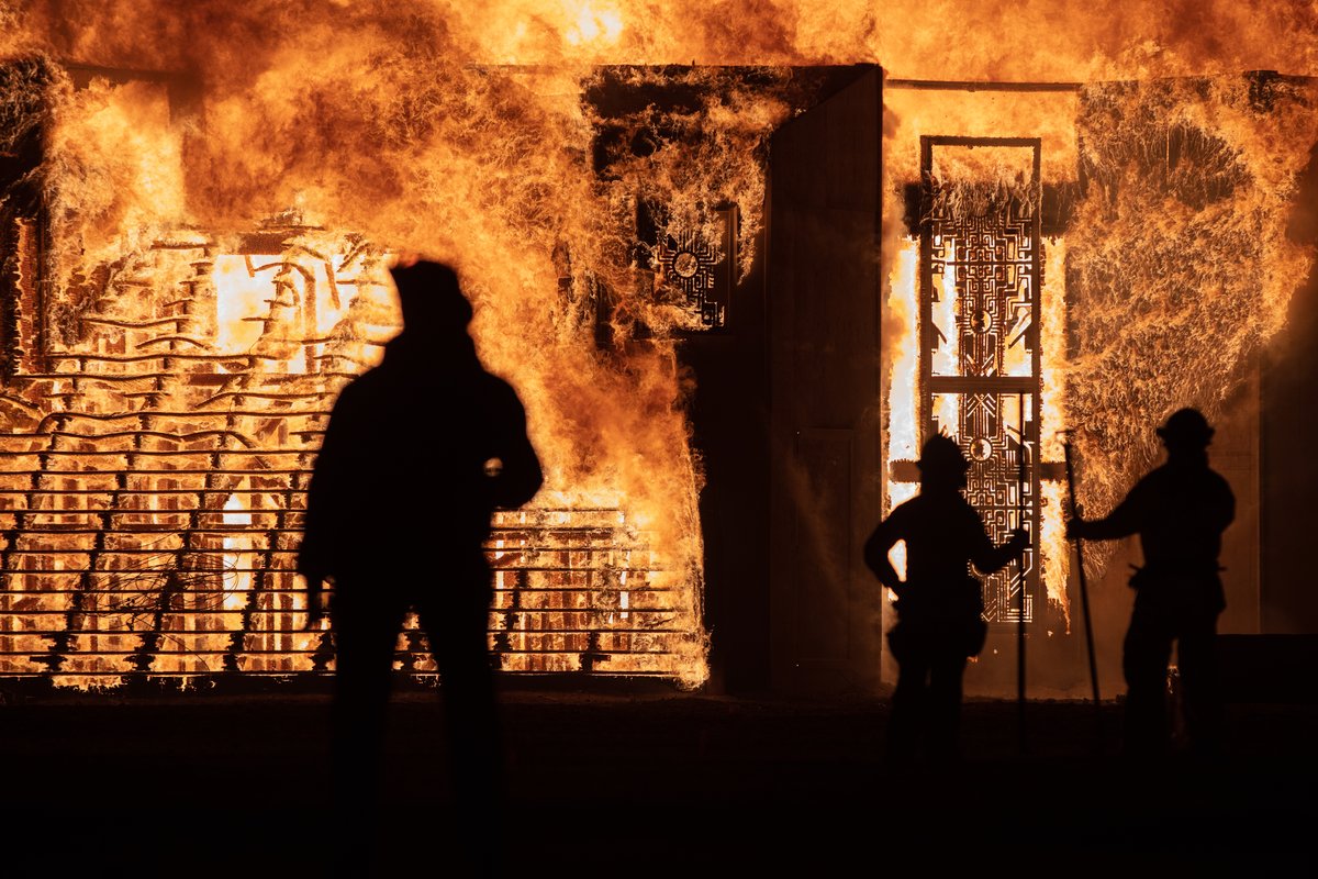 Silhouettes of sandmen and fire safety people as the man burns.