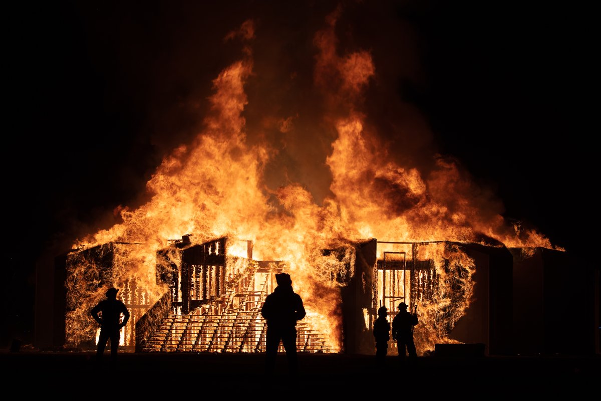 Silhouettes of sandmen and fire safety people as the man burns.