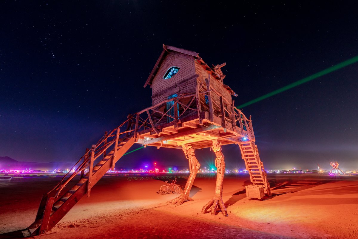 Baba Yaga's House by: Jessi Sprocket Janusee and Baba Yaga's Book Club from: Reno, NV year: 2018 The house of Baba Yaga will rise from the playa straddling it's mechanical chicken legs. The crone's house will be poised to run at the slightest provocation. Ascend her staircases to test the old witch if you dare. Are you able to walk through the veil of mortality into the space where the seer dwells? If you are strong of will, feeling bold and willing to show vulnerability she may allow you to venture within her sanctum. URL: http://jessisprocket.com/baba-yaga/