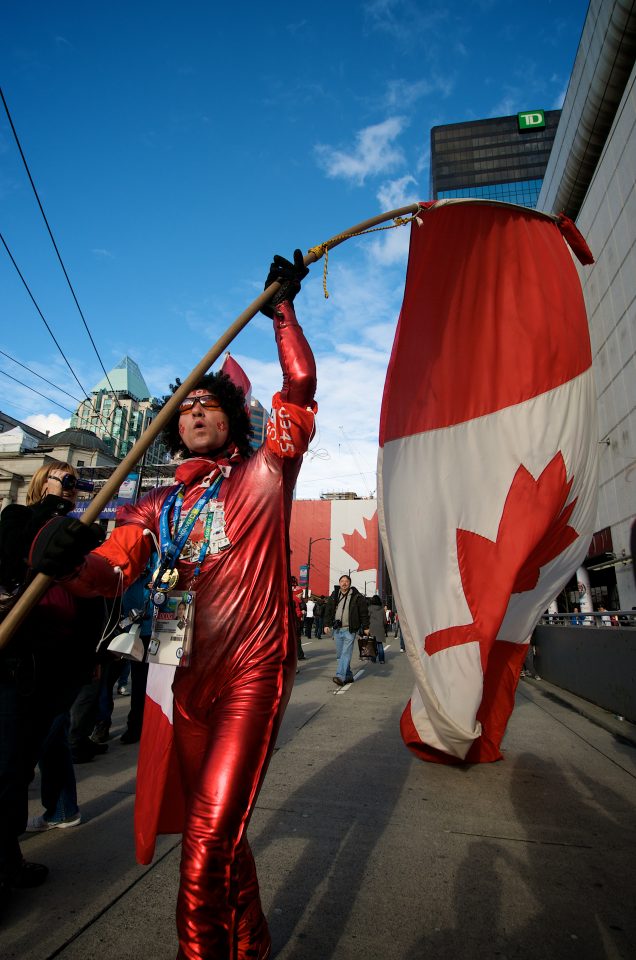 Man Carries Large Canadian Flag and Wears Onesie