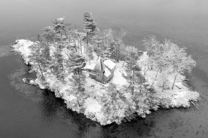 Snow Covered Cottage With Spire on Small Island