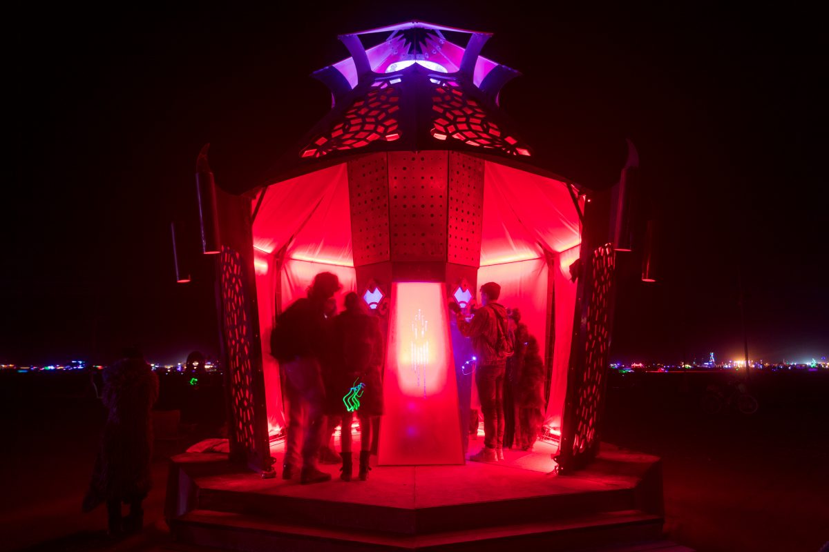 The Harmoniscope from: Seattle, WA year: 2016  The Harmoniscope is a 20′ tall mysteriously pulsing 9-sided structure that transports participants to another place in space-time. Inside is an 8-sided column containing a reactor core made up of many colorful spiraling acrylic rods, the light from w...