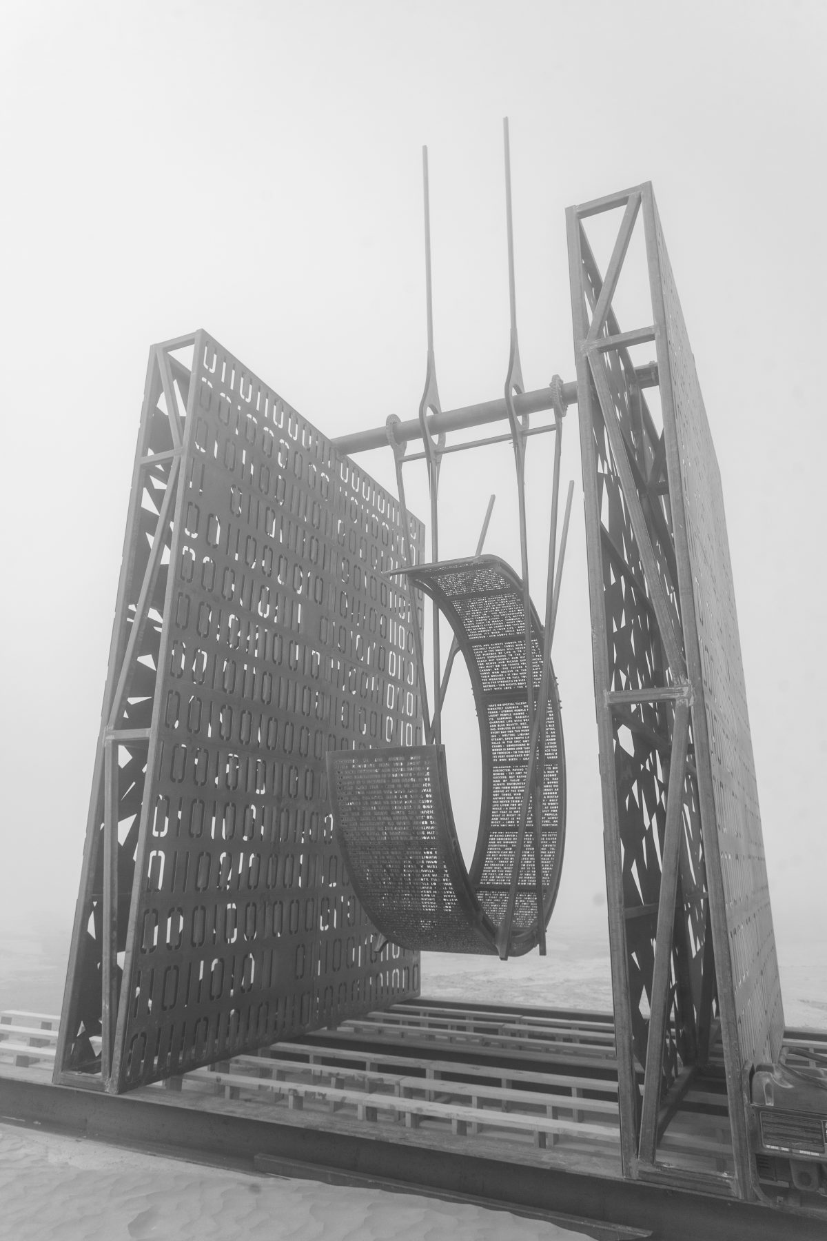 Kinesios by: ND Collective from: Nashville, TN year: 2018  Kinesios is an imposing steel colossus formed by two internally lit vertical steel planes set parallel to each other. Perforated with a binary code on one side and a chaotic pattern on the other side the two planes support a hanging sculp...