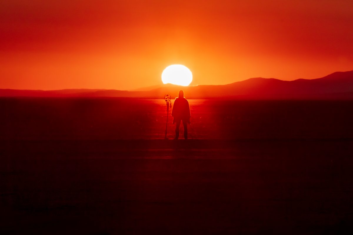 Lone burner with sun rising at the trash fence.