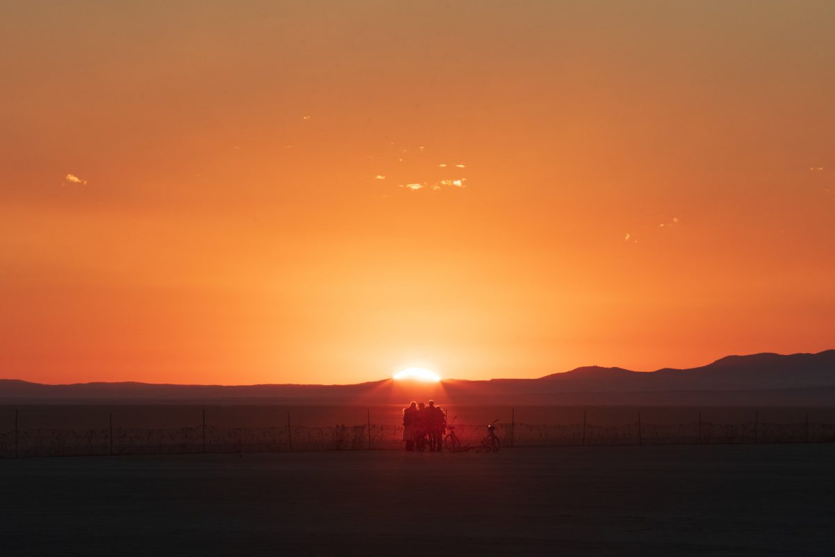 Burners gather for sunrise at the trash fence.