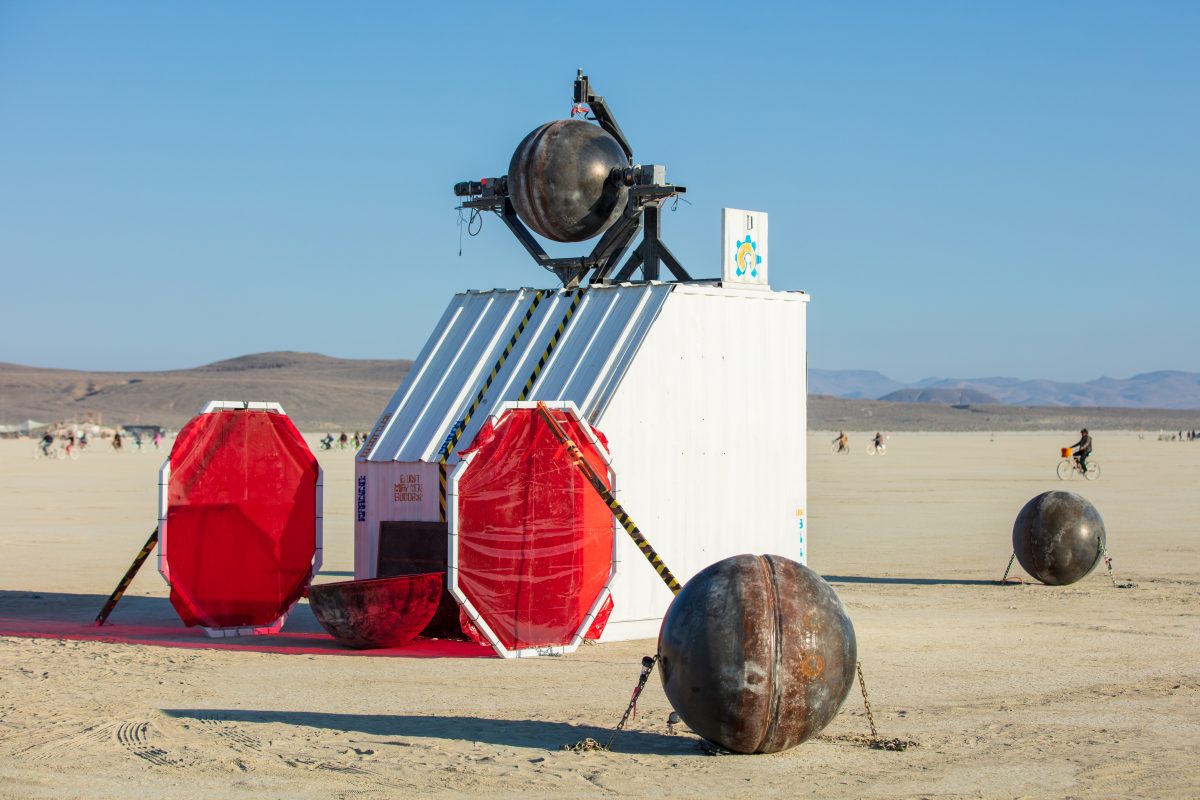 Ei Robot by: Spencer Edgerton, Launchpad Artspace at 3113 Studios, and Camp Deep Orbit from: Tucson, AZ year: 2018  A robot sits on a box and carves ideas into steel balls. The finished openwork balls surround the main robot sculpture and glow with an inner light, projecting the image of their ne...