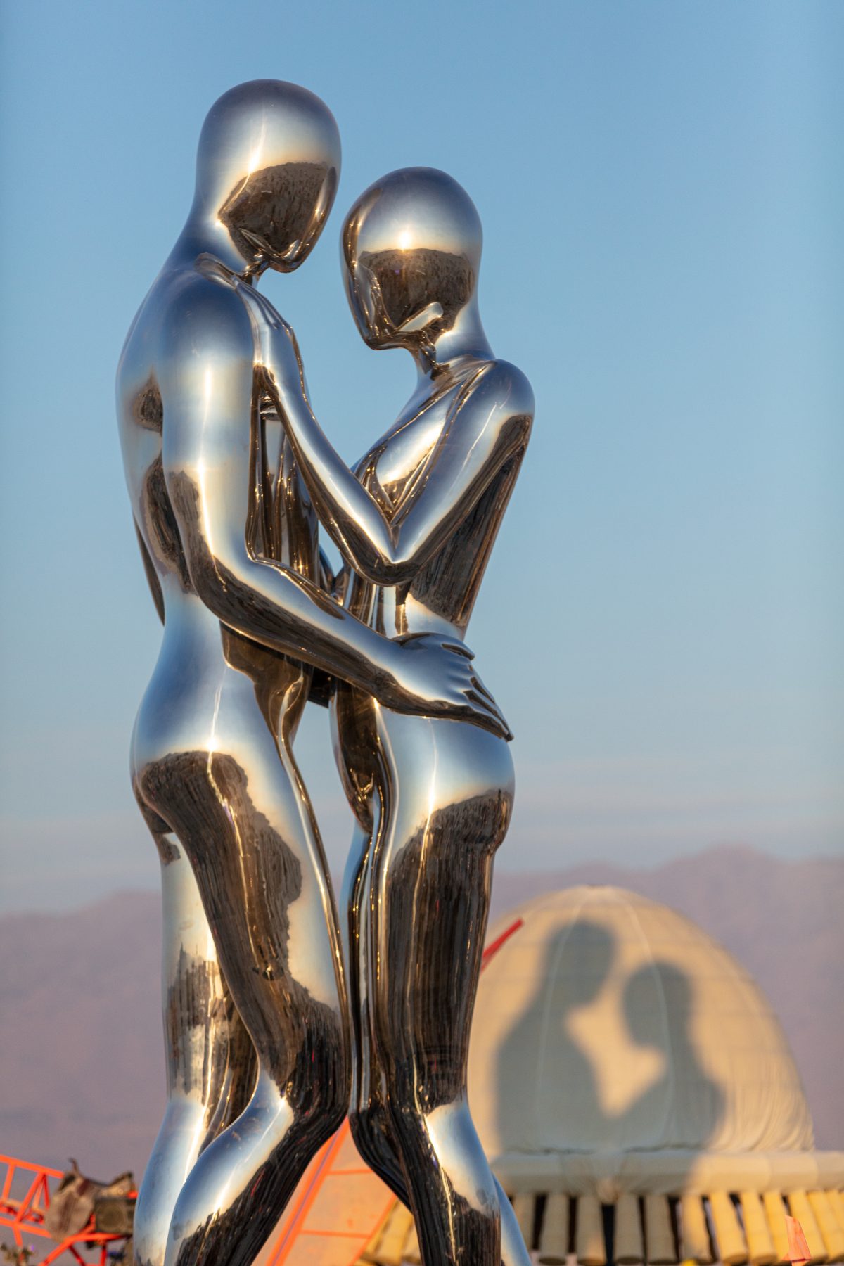 SENTIENT AI by: Michael Benisty, Love and Unity from: Brooklyn, NY year: 2018  A sculptural representation of Male and Female holding one another in a symbolic and universal position of caring in a display of Love and Unity. Measuring 25 feet tall and made out of mirror polished stainless steel. ...