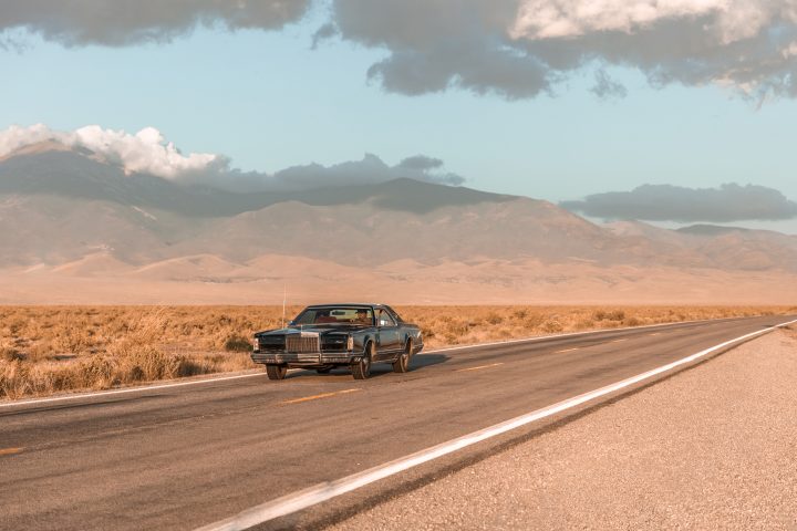 Man Driving Vintage Car on the Loneliest Road