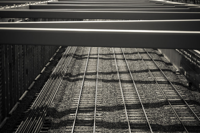 Boxed-In Train Tracks Beneath Overhead Beams
