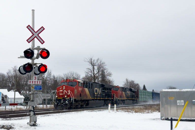Freight Train Passing Winter Rail Crossing with Red Signal