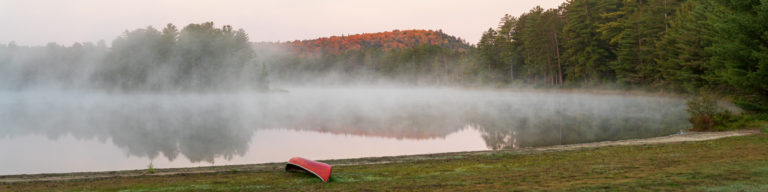 Red Canoe by a Foggy Lakeshore in Autumn