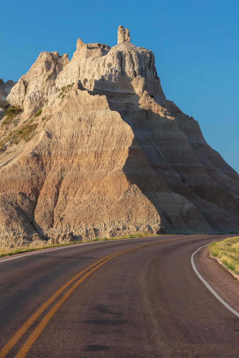 Layered Badlands Butte Beside Winding Road